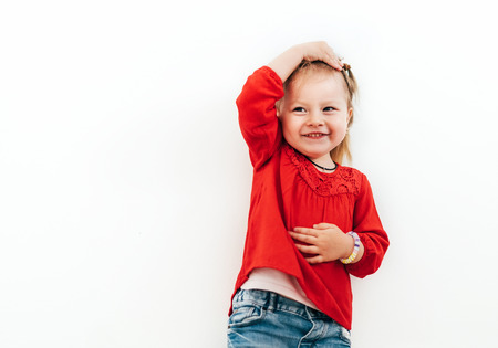 Little girl dressed red blouse on the white background. Confused emotions concept image.の写真素材