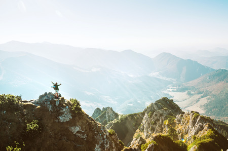 Mountain hiker with backpack tiny figurine stands on mountain peak with beautiful panoramaの写真素材