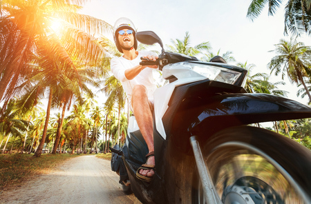 Man riding motorbike under palm treesの写真素材
