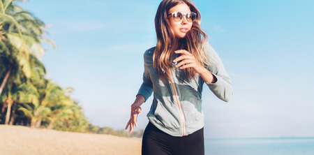 Fashionable young longhaired woman have morning jogging on the seaside beachの写真素材