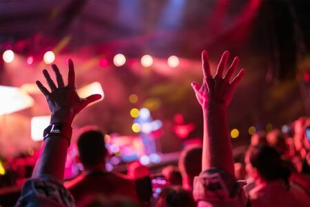 Young teenager girl raised up two hands supporting favorite popular band on the night concert.の写真素材