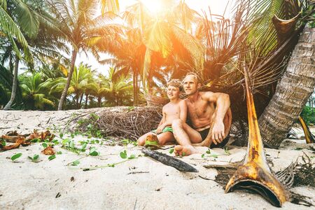 Father and son sit together on selfmade hut and playing as Robinzonesの写真素材