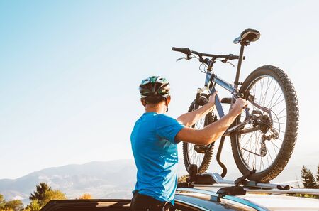 Mountain biker man take of his bike from the car roofの写真素材