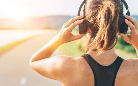 Close up image of teenager adjusting  wireless headphones before starting jogging and listening to musicの写真素材