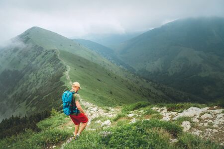 Backpacker hiker man walking by the foggy cloudy weather mountain range path with backpack.の写真素材