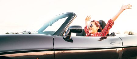 Young cheerful smiling female driving convertible car at sunny day time headers web siteの写真素材
