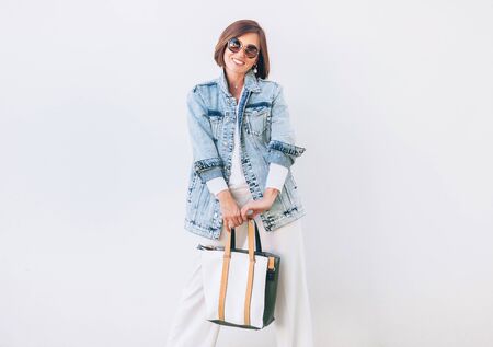 Woman dressed elegant outfit with oversize denim jacket and shopper bag. Modern fashion outfit concept image.の写真素材