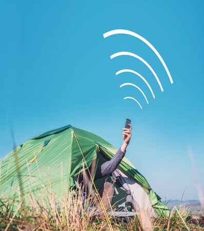 Traveler sits in touristic tent and try to catch cellular networkの写真素材