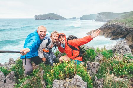 Happy travelers two parents family with their little son on the Cantabrian Sea coast cheerfully...