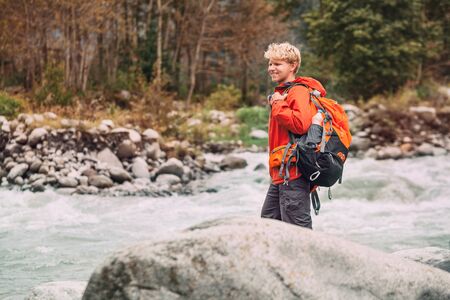 Young man tourist in mountain forest on the river bankの写真素材