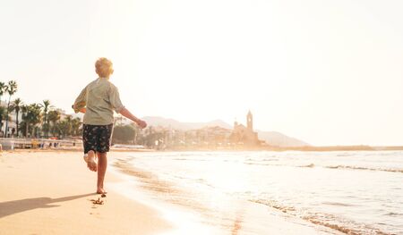 Happy little boy running by Mediterranean spain coast in Sitges town near Barcelonaの写真素材