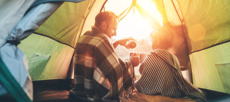 Father and son drink hot tea sitting together in camping tentの写真素材