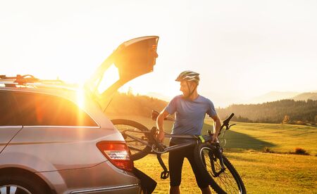 Young Man puting his bicycle in the trunk of a carの写真素材