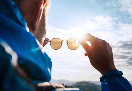 Backpacker man looking at bright sun through polarized sunglasses  enjoying mountain landscape.の写真素材