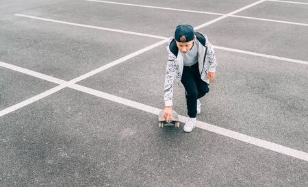 Teenager skateboarder boy with a skateboard on asphalt playground doing tricks.の写真素材