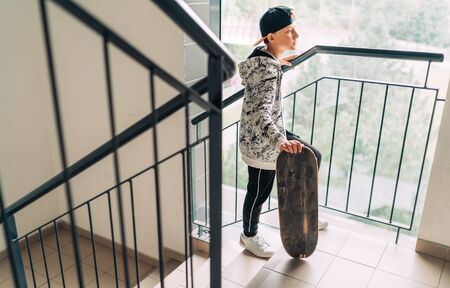 Teenager skateboarder boy with a skateboard going up by staircase home.の写真素材