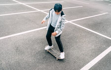 Teenager skateboarder boy with a skateboard on asphalt playground doing tricks.の写真素材