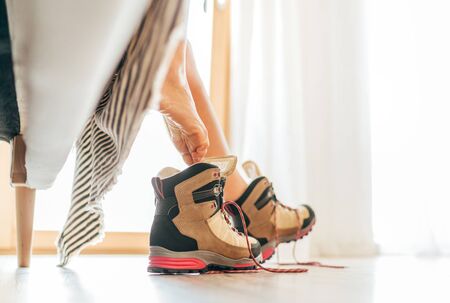 Young sexy barefoot female putting on a New trekking boots with untying laces under the bad view in the bright sunlight morning new day.の写真素材