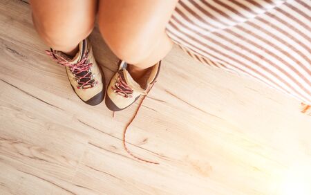 Young sexy female putted on a New trekking boots with untying laces top view in the bright sunlight morning new day.の写真素材