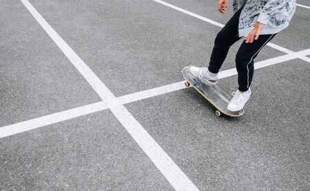 Teenager skateboarder boy with a skateboard on asphalt playground doing tricks.の写真素材