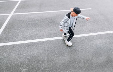 Teenager skateboarder boy with a skateboard on asphalt playground doing tricks.の写真素材
