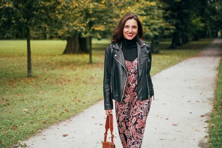 Smiling female dressed boho fashion style colorful long dress with black leather  jacketの写真素材