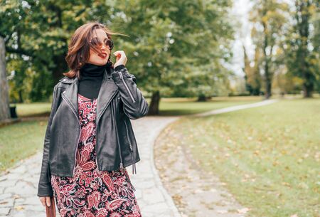 Smiling female dressed boho fashion style colorful long dress with black leather  jacketの写真素材