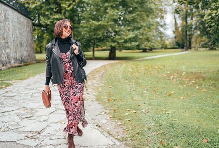 Smiling female dressed boho fashion style colorful long dress with black leather  jacketの写真素材