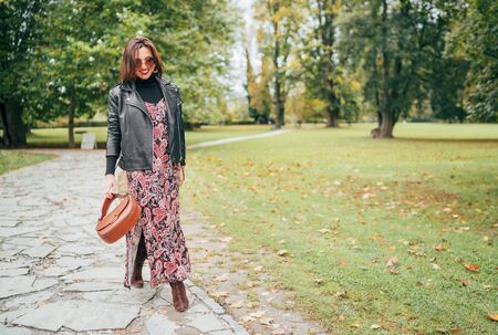 Smiling female dressed boho fashion style colorful long dress with black leather  jacketの写真素材
