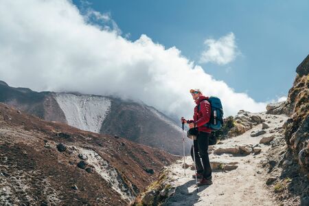 Hiker man silhouette on clouds background standing on path going over the Imja Khola valley and enjoying mountain views during an Everest Base Camp trekking route near Tengboche. Active vacation imageの写真素材