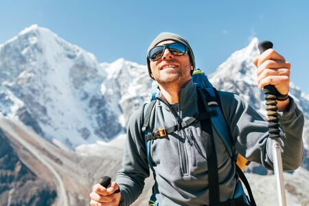 Portrait of smiling Hiker man on Taboche 6495m and Cholatse 6440m peaks  with trekking poles, UV protecting sunglasses.の写真素材