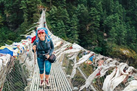 Young smiling female photographer crossing canyon over Suspension Bridgeの写真素材