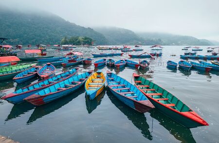 Multicolored traditional rowboats on the morning lake water in Pokhara, Gandaki Pradesh, Nepal. Asian traveling concept image.の写真素材