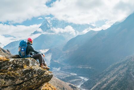 Young hiker backpacker female sitting on the cliff edge and enjoying Ama Dablam 6,812m peak viewの写真素材