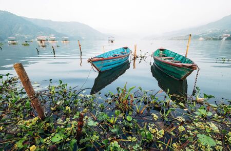 Multicolored traditional rowboats on the morning lake water at LakeSide in Pokhara, Gandaki Pradesh, Nepal.の写真素材
