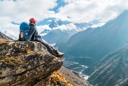 Young hiker backpacker female sitting on the cliff edgeの写真素材