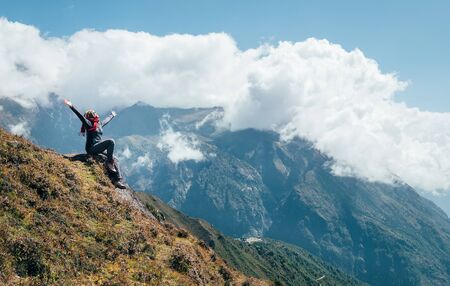 Young hiker backpacker female rising her arms, cheerful laughing and enjoying valley during high altitudeの写真素材