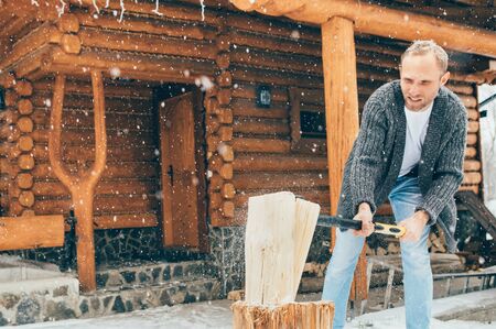 Man chopping wood on snowy yard for fireplace.の写真素材