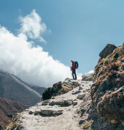 Hiker man silhouette on clouds standing on path going over the Imja Khola valleyの写真素材