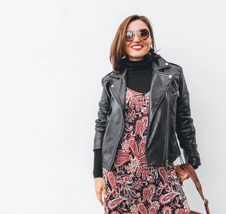 Smiling female dressed boho fashion style colorful long dress with black leather jacketの写真素材