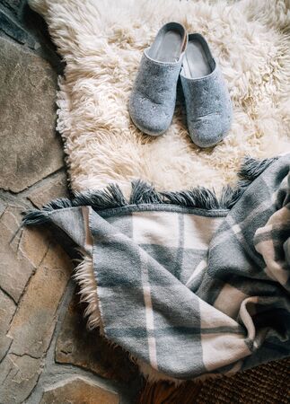 The pair of gray home slippers on the natural white sheep sheepskinの写真素材