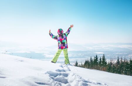 Happy little girl jumping on the deep snow hill with a great over city viewの写真素材