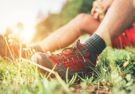 Backpacker's trekking boots close up shot. Man has a rest break sitting on green grass and enjoying mountain walkingの写真素材