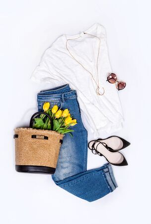 Spring summer basic denim casual city trend outfit set for woman: jeans, blouse, shoes, golden necklace, sunglasses and handbag full of yellow tulips.の写真素材
