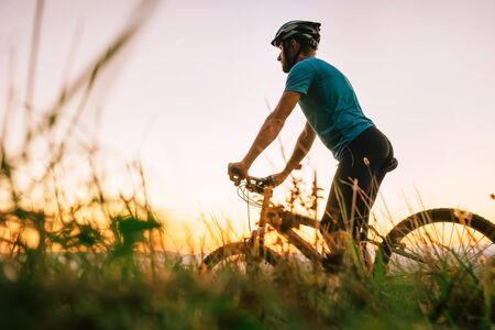 Man biker man meets a sunset on top of hillの写真素材