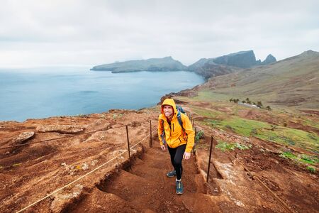 Young male backpacker hiking by footpath on Sao Lourenco headland with Atlantic ocean bay view in the end of February, Madeira island, Portugal. Active people around  World traveling concept image.の写真素材