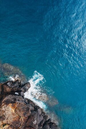 Top aerial view of turquoise Atlantic ocean water waves crashing on rocksの写真素材