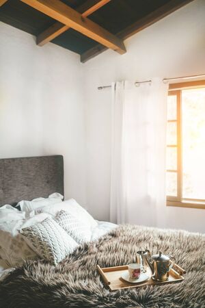 Cozy bedroom shot with coffee pot and cup on the fir bed blanketの写真素材