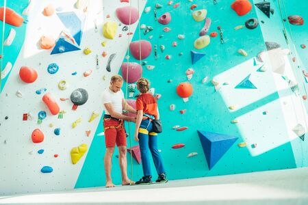 Father helping his teenage son and checking climbing harness near the indoor climbing wall. Boy preparing
for a climbing. Happy parenting concept image.の写真素材
