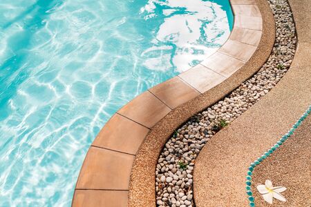 Curved swimming pool paved edge with pebbles. Clean transparent pool water wavesの写真素材